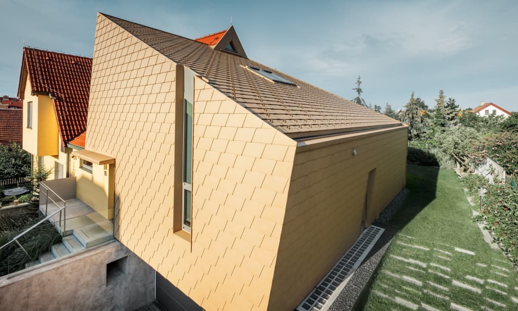 Ein Einfamilienhaus in Prag, gedeckt mit gelben Dach- und Wandschindeln aus Aluminium