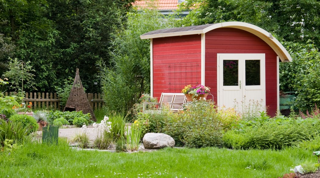 Rotes Holz-Gartenhaus mit halben Tonnendach aus Dachpappe.