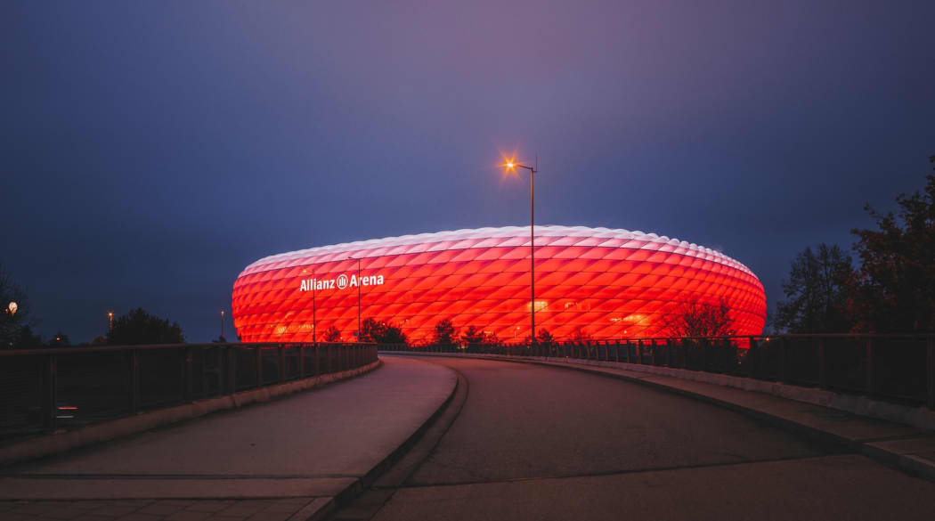 Rot erleuchtete Alianz Arena in München von der Straße aus fotografiert